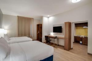 ein Hotelzimmer mit 2 Betten und einem Schreibtisch mit einem TV in der Unterkunft MainStay Suites Carlisle - Harrisburg in Carlisle