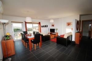 a dining room and living room with a table and chairs at Solar - Sea view apartment with pool in São Martinho do Porto