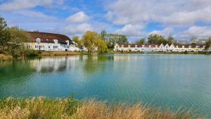 a large body of water with houses in the background at Charming Lake House nature retreat in Cotswold Water Park, South Cerney near Cirencester in Cirencester