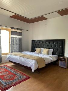 a bedroom with a large bed with a black headboard at Hotel Nubra Delight and Camps in Hundar