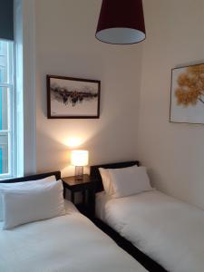 two beds in a room with a lamp on a table at St James Quarter 2 Bed Apartment in Edinburgh