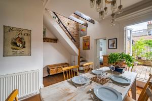 a dining room with a wooden table and chairs at Charming home with roof terrace in East London by UnderTheDoormat in London
