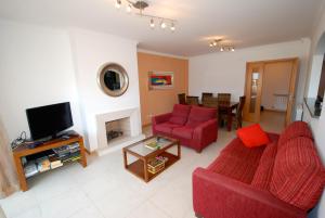 een woonkamer met twee rode banken en een tv bij Turtle - 3 bedroom apartment in Nazaré with 2 shared pools and private terrace in Nazaré