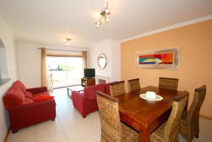 een woonkamer met een houten tafel en rode stoelen bij Turtle - 3 bedroom apartment in Nazaré with 2 shared pools and private terrace in Nazaré