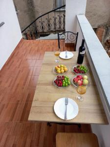 een houten tafel met borden met fruit en wijnglazen bij ApartHotel RioNi in Koetaisi