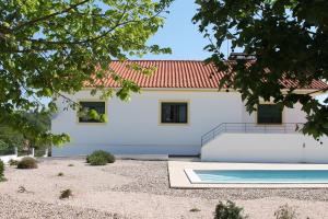 a white house with a red roof and a swimming pool at Herdade dos Templários in Tomar