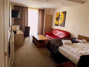 a hotel room with a bed and a red chair at Arenia Łeba -Filia Kompleksu ARENA SŁOŃCA in Łeba