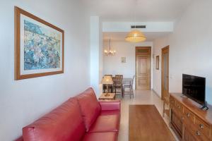 a living room with a red couch and a television at Sea You Apartamentos Valencia Port Saplaya in Port Saplaya