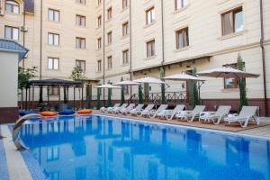 a swimming pool with chairs and umbrellas next to a building at Navruz Hotel Tashkent in Tashkent