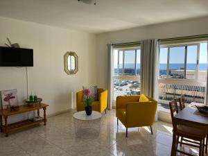 a living room with yellow chairs and a view of the ocean at CORNELIA´S HOME TC3 Atico vista maravillosa in Los Cristianos