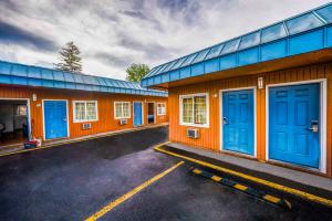 a row of buildings with blue doors in a parking lot at Royal Gateway Motel by OYO in Bend