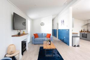 ein Wohnzimmer mit einem blauen Sofa und einem TV in der Unterkunft Lavender Lodge, 8 Roadford Lake Lodges in Lifton
