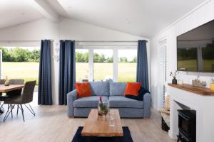 - un salon avec un canapé bleu et une table dans l'établissement Lavender Lodge, 8 Roadford Lake Lodges, à Lifton