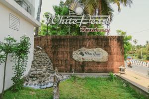 a sign for a hotel with a rock wall at White Pearl Residency in Puducherry