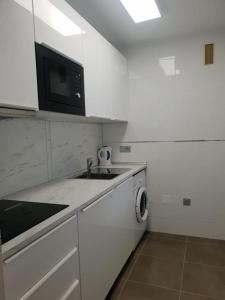 a white kitchen with a sink and a microwave at Ático - Edificio Marina Banús- Calle Muelle de Ribera in Marbella