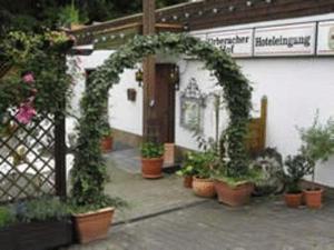 an arch with plants in pots in front of a building at Urberacher Hof in Rödermark