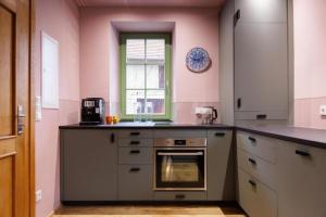 a kitchen with pink walls and a stove and a window at Ferienhaus Monteverde in Meddersheim