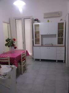 uma cozinha com uma mesa e armários brancos e uma mesa e cadeiras em Casa Giada em Porto Cesareo