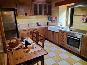 cocina con mesa de madera y cocina con fregadero en Casa Rural Sensaciones 3 dormitorios con jardin, en Carrocera