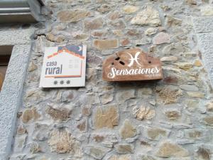 una señal en el lateral de un edificio de piedra en Casa Rural Sensaciones 3 dormitorios con jardin en Carrocera
