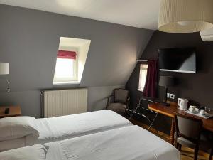 a hotel room with two beds and a desk and a window at Hotel Restaurant Au Cerf d'Or in Strasbourg