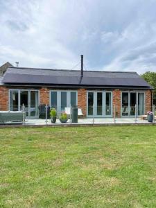 une maison en briques avec un toit solaire sur une cour dans l'établissement Lodge Barn Annexe, 