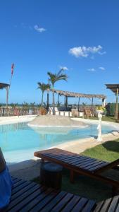 un banco de madera sentado junto a una piscina en Apartamento com vista para o mar, piscina , deck , playground e estacionamento ., en Taíba