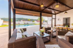 uma sala de estar exterior com sofás e uma piscina em La Era Gran casa de vacaciones para grupos adaptada a vuestras necesidades em Rute