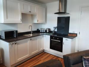 a kitchen with white cabinets and a black appliance at CRAIGLEA HEATHER in Killin