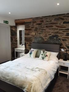 a bedroom with a large bed with a stone wall at CRAIGLEA HEATHER in Killin