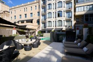 eine Terrasse mit Stühlen und Tischen sowie ein Gebäude in der Unterkunft Catalonia Passeig de Gràcia 4* Sup in Barcelona