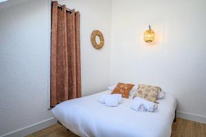 - un lit blanc avec des serviettes dans l'établissement LE BEG ER LANN - Appartement contemporain centre ville Sarzeau, à Sarzeau