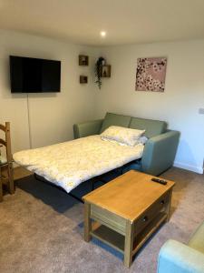 a bed and a couch in a room with a table at No 28C St Benedict in Glastonbury