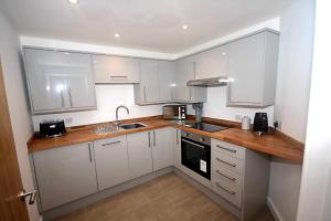 a kitchen with white cabinets and a wooden counter top at No 28C St Benedict in Glastonbury
