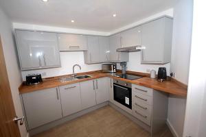 cocina con armarios blancos y encimera de madera en No 28C St Benedict en Glastonbury