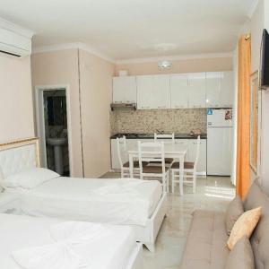 Vila Vitoria في Shëngjin: غرفة بسريرين ومطبخ مع طاولة