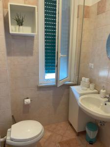 a bathroom with a toilet and a sink and a window at Ostia Bed and Beach in Lido di Ostia