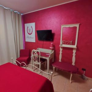 1 dormitorio con pared roja, espejo y sillas rojas en MAISON PLATONE en Alessandria