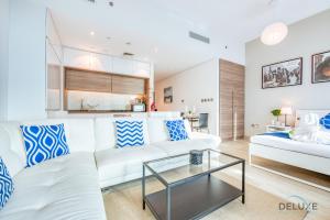 ドバイにあるAiry Studio in Studio One Dubai Marina by Deluxe Holiday Homesのリビングルーム(白いソファ、ガラスのテーブル付)