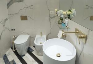 a white bathroom with a toilet and a sink at Hotel Cala Moresca in Bacoli