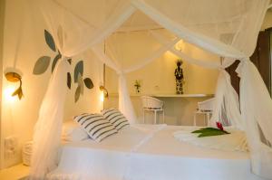 1 dormitorio con 1 cama blanca con cortinas blancas en Pousada Jacarandá by Rivaj, en Trancoso