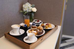 a tray with plates of pastries and cups of coffee at Hotel Cala Moresca in Bacoli