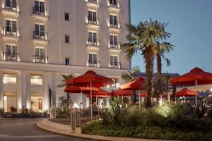 a hotel with red umbrellas in front of a building at Grand Hotel Palace in Thessaloniki