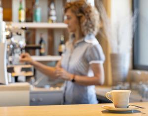 a woman in a kitchen with a coffee cup on a table at Hotel Constellation in Lido di Savio