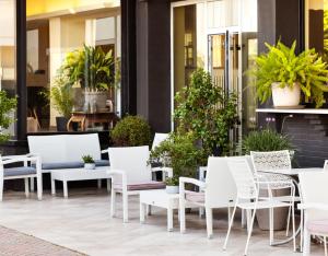 eine Terrasse mit weißen Stühlen, Tischen und Topfpflanzen in der Unterkunft Hotel Constellation in Lido di Savio