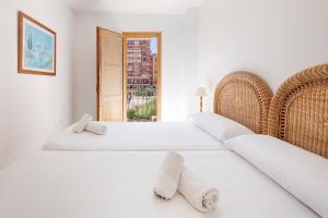 a white bedroom with two beds and a window at Sea You Apartamentos Valencia Port Saplaya in Port Saplaya