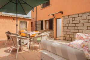 een patio met een tafel en stoelen en een parasol bij Casa Bice 2 in Golfo Aranci