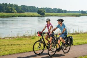 um homem e uma mulher a andar de bicicleta por um caminho ao lado de um rio em Ferienwohnung Alt Freyburg em Freyburg