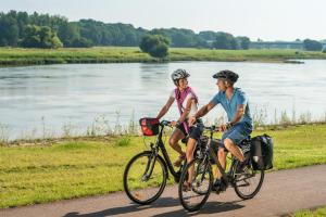 a man and woman riding bikes down a path next to a river at Ferienwohnung Alt Freyburg in Freyburg