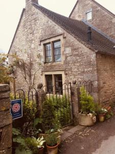 une ancienne maison en pierre avec un portail et des plantes dans l'établissement Dove Cottage, à Bisley